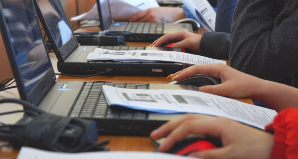 people looking at documents and information on laptops