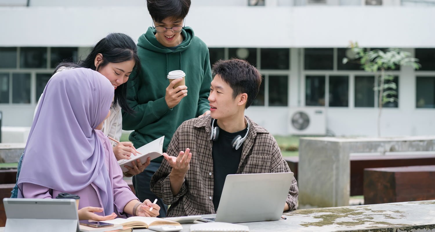 Multi ethnic group of university students brainstorming together outdoors at campus