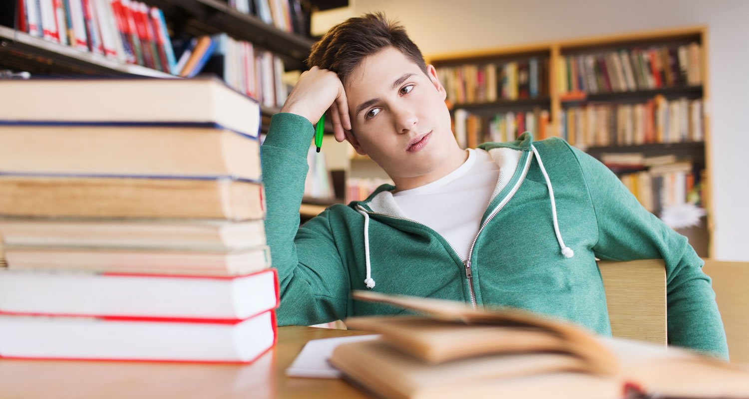 Stressed looking student slumped in front of books